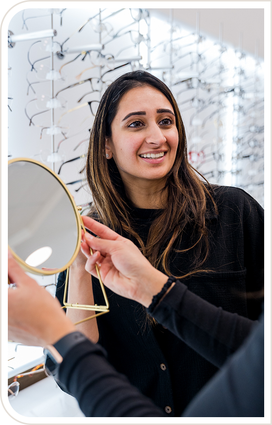 Woman smiling at another woman who is holding a mirror