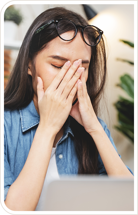 Woman placing holds over eyes with glasses propped up on forehead