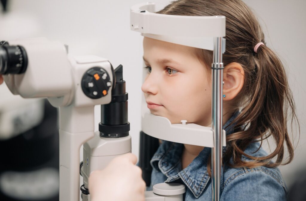 A young child positioned at a slit lamp machine during a back-to-school vision checkup.