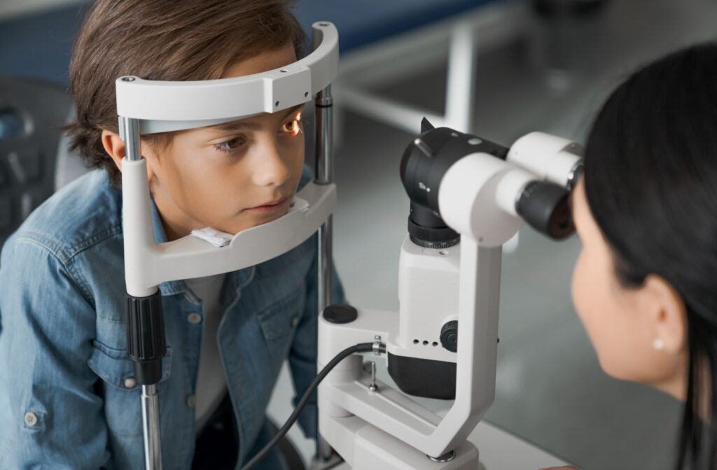 Young boy undergoing an eye exam with a phoropter at an optometrist’s.