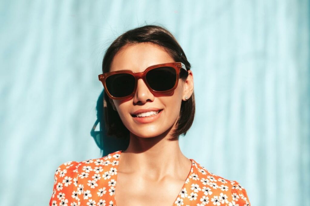 Smiling woman wearing trendy sunglasses outside in the sun.