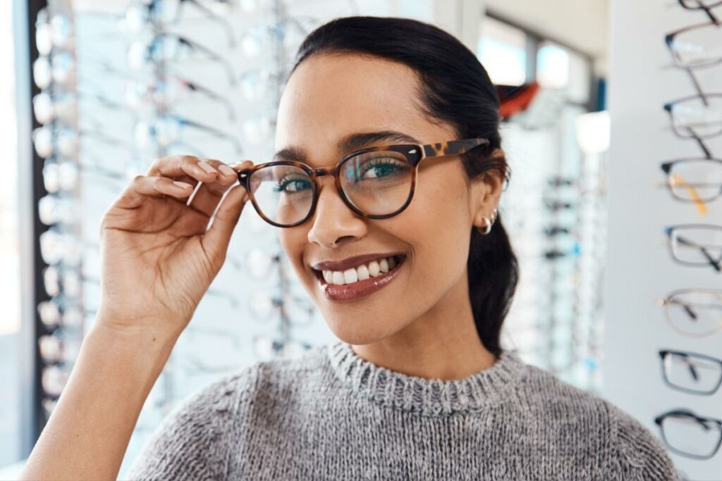 Happy woman trying on glasses at the optometrist office.